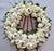 Sympathy Wreath--This beautiful flower arrangement contains: 6 Stem White Lily 30 White Carnation 20 White Rose Seasonal fillers Some of the Lilies may arrive in bud form, ready to bloom into full beauty in 2-4 days. Lily color will be replaced with best available color of equal value. While we always strive to ensure that products are accurately represented in our photographs, from season to season and subject to availability, our florists may be required to substitute one or more flowers for a variety of equal or greater quality, appearance and value. 